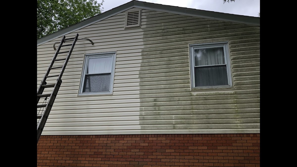 A house's vinyl siding, half still covered in green algae grime and half freshly pressure washed clean, in one photo